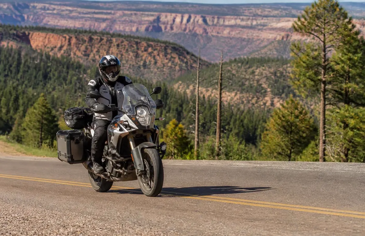Adventure motorcycle on a high-elevation highway above pine forest and red cliffs near Enoch — motorcycle insurance for Enoch, Utah riders