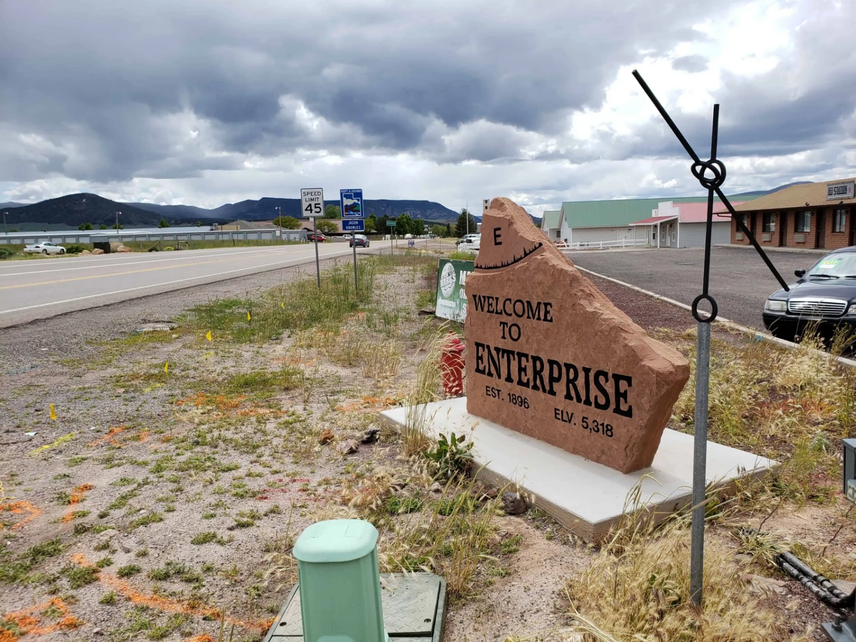 Welcome to Enterprise, Utah stone monument along the highway with mountains and prairie in the background — auto insurance for Enterprise drivers