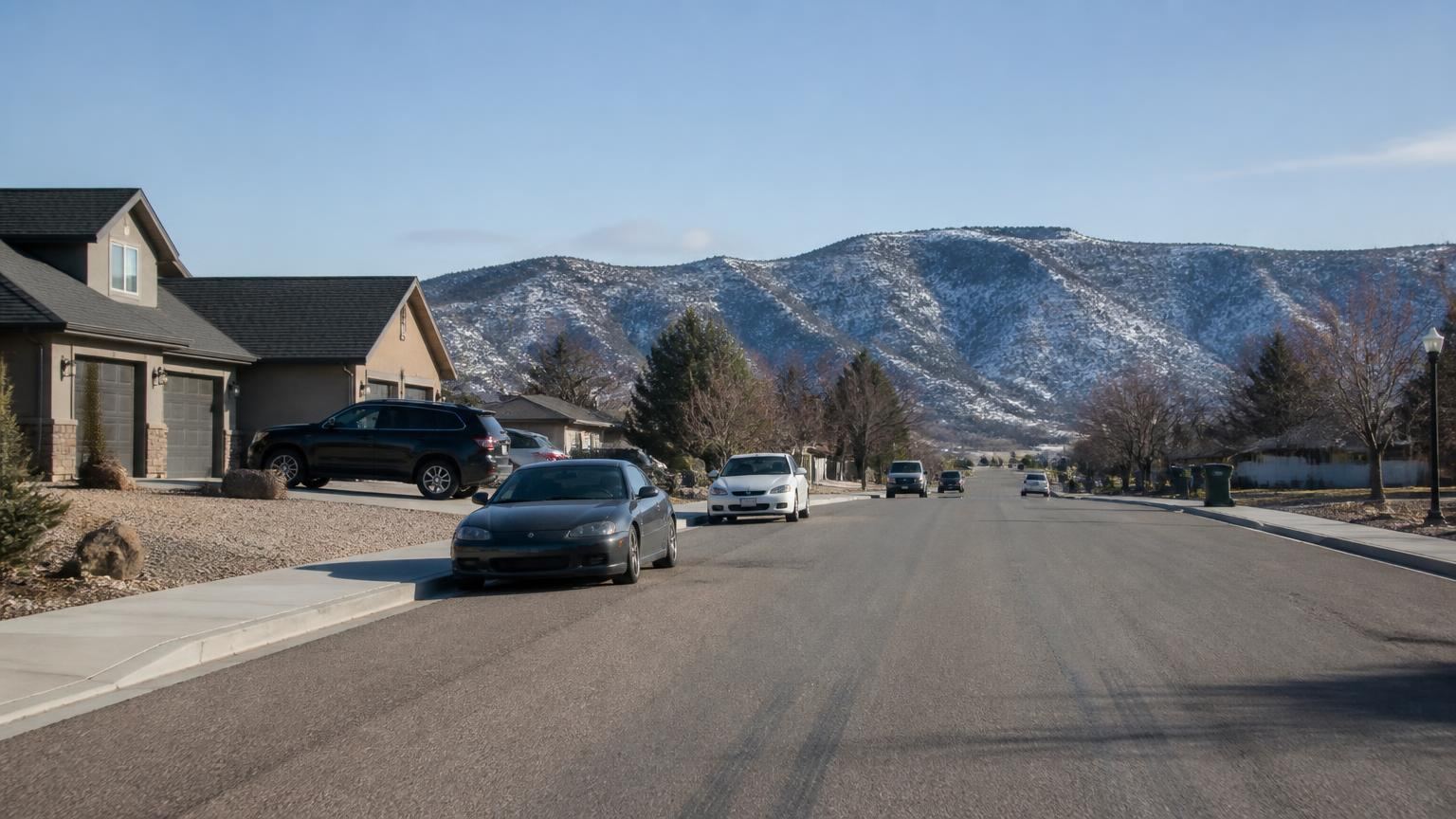 Car insurance in Enoch, Utah (84721) — Cedar Valley farm fields and a rural highway with snow-dusted Iron County mountains behind