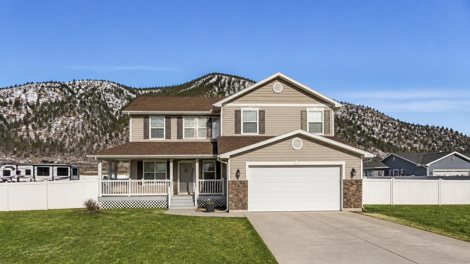 Homeowners insurance in Enoch, Utah (84721) — a two-story suburban home in Enoch, Utah with the snow-capped Cedar Mountain foothills behind