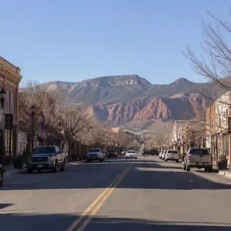 Historic Main Street in downtown Cedar City, Utah, with red-rock cliffs glowing behind — the largest city in Iron County