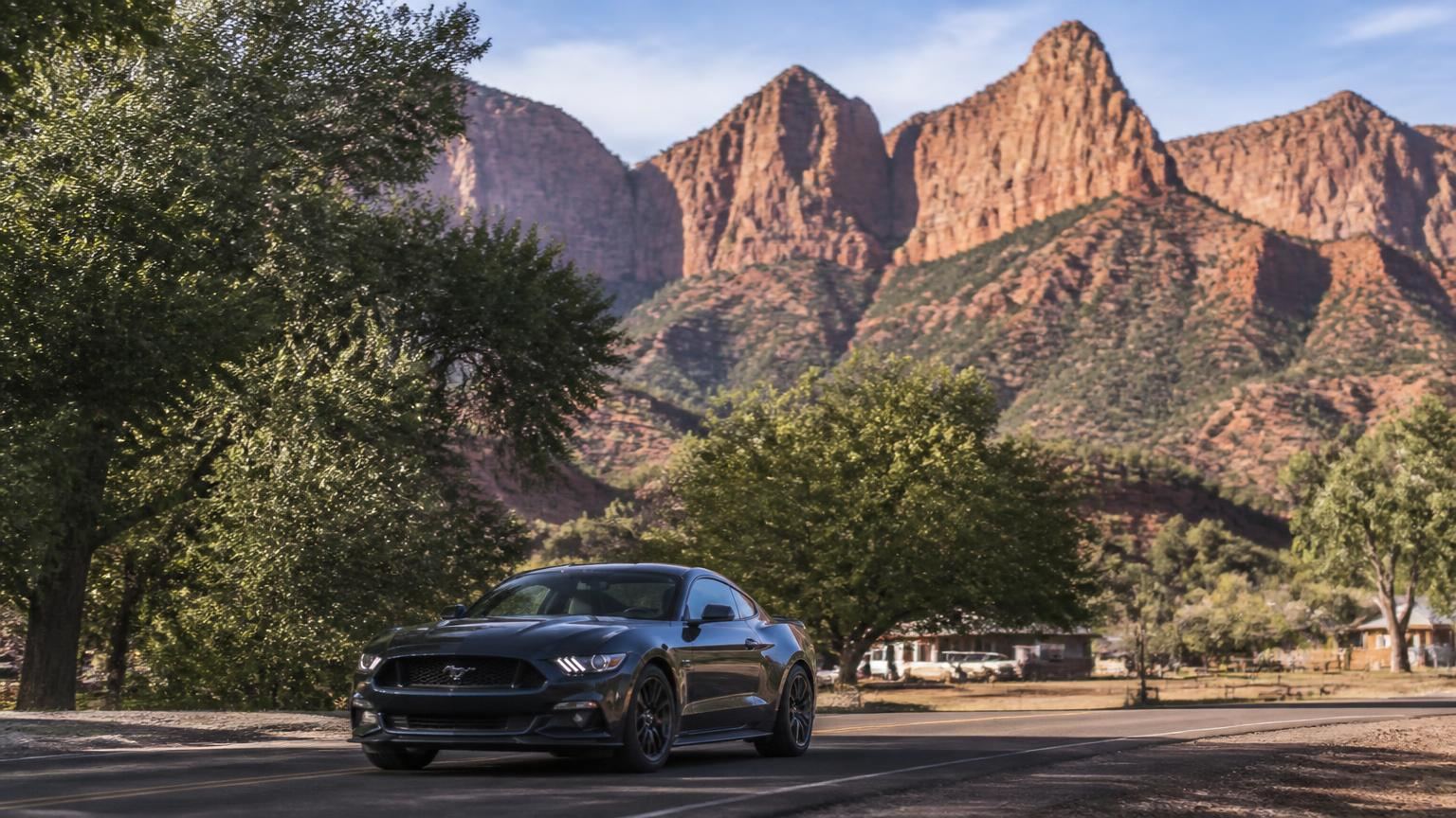 Car insurance in Kanarraville, Utah (84742) — hay fields and a quiet lane beneath the steep red cliffs of Kanarra Mountain